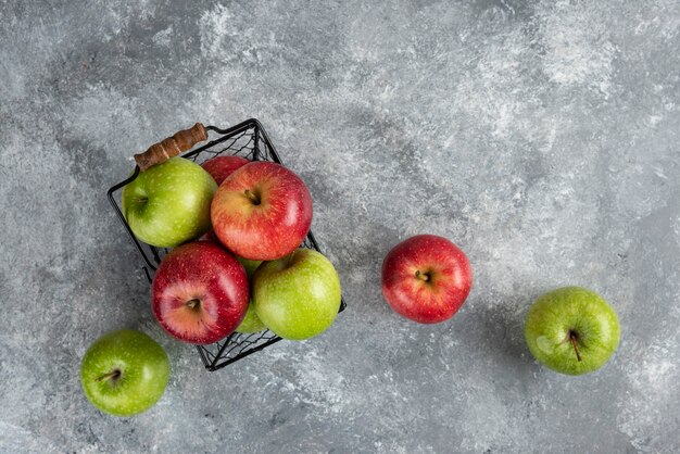Bündel frische grüne und rote Äpfel in Metallkorb gelegt.