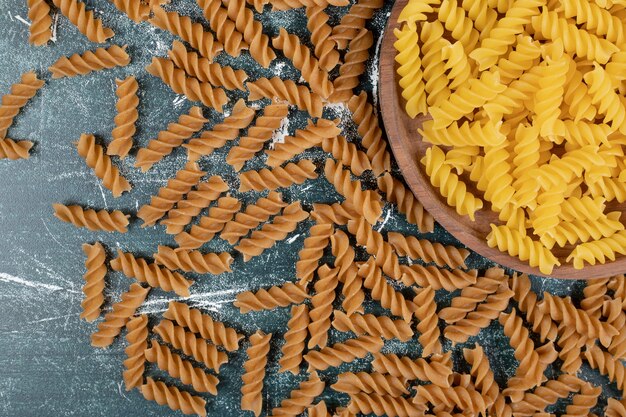 Bündel gelbe und braune Fusilli-Nudeln auf blauem Hintergrund. Hochwertiges Foto