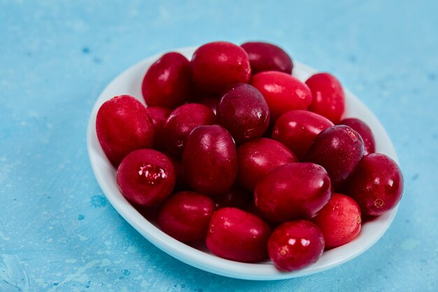 Bündel Kornelkirschenbeeren auf weißem Teller. Nahansicht.