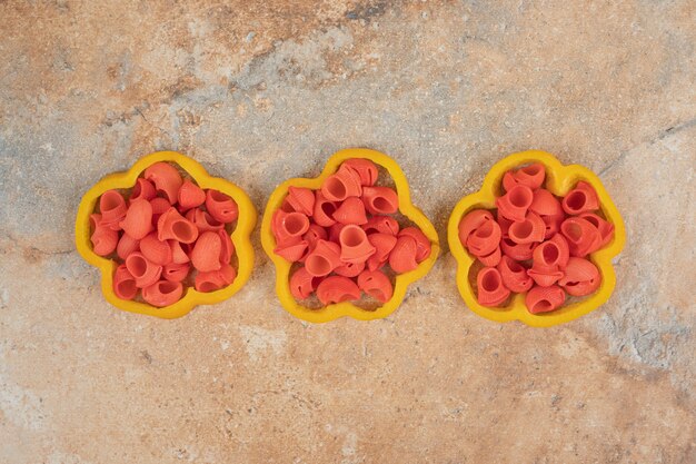 Bündel Nudeln in Paprika-Scheiben auf orangefarbenem Hintergrund