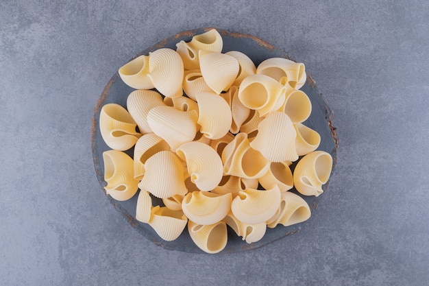 Kostenloses Foto bündel rohe muschelnudeln auf holzstück.