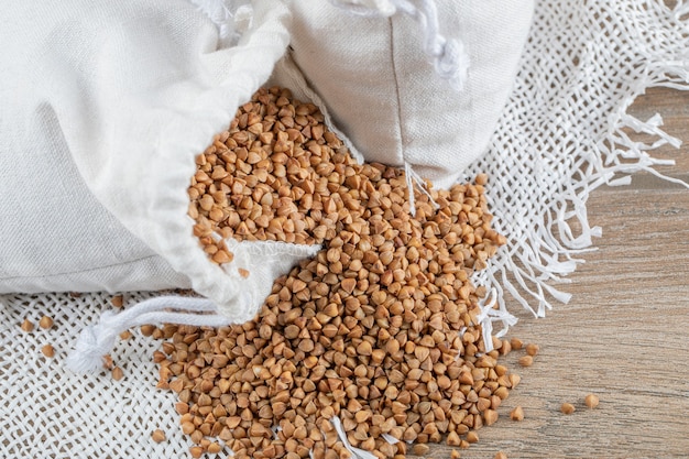 Bündel roher Buchweizen aus weißem Sack mit Löffel.