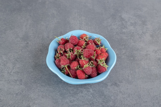 Bündel rote Himbeeren in blauer Schüssel. Foto in hoher Qualität