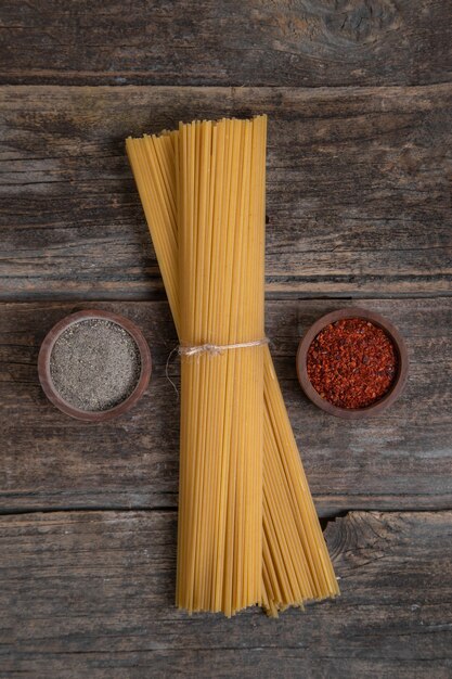 Bündel trockener ungekochter Spaghetti und Gewürze auf Holzoberfläche gelegt. Hochwertiges Foto