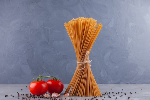 Bündel Vollkorn-Spaghetti mit Seil und frischen roten Tomaten.