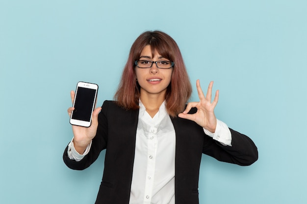 Büroangestellter der Vorderansicht, der Telefon auf blauer Oberfläche hält