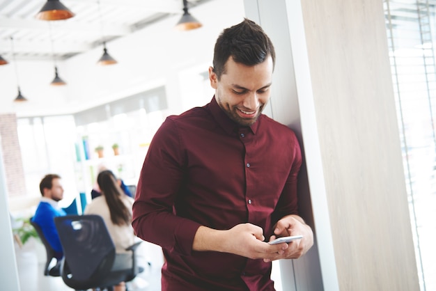 Büroangestellter, der während der Arbeit mit dem Handy chattet