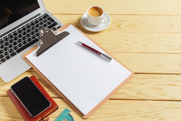 Bürotischhintergrund mit Kaffeetasse, Bleistiften und Computertastatur. Geschäftsarbeitsplatz oder Arbeitsplatzkonzept.