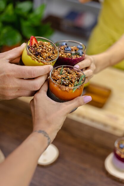 Bunt gesundes Frühstück süße Desserts wenige verschiedene Chia Pudding in Gläsern auf Holztisch in der Küche zu Hause.