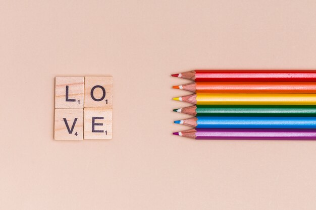 Bunte Bleistifte des Regenbogens und Liebesbriefe auf beige Hintergrund