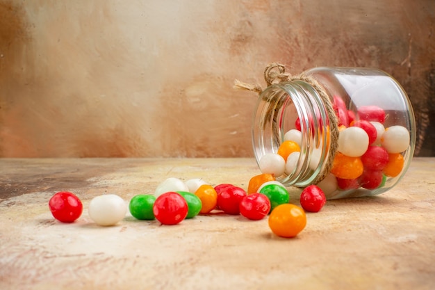 Kostenloses Foto bunte bonbons der vorderansicht innerhalb der glasdose auf hellem hintergrund