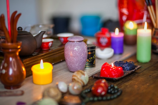 Bunte brennende Kerzen; keramische Vase und chinesische Kugeln der Therapien über Holztisch