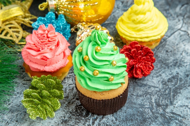 Bunte Cupcakes-Weihnachtsverzierungen der Vorderansicht auf grauem Foto des neuen Jahres