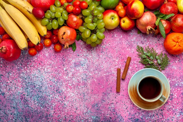 Bunte Früchte der Frischobstzusammensetzung der Draufsicht mit Tee auf hellrosa Oberfläche