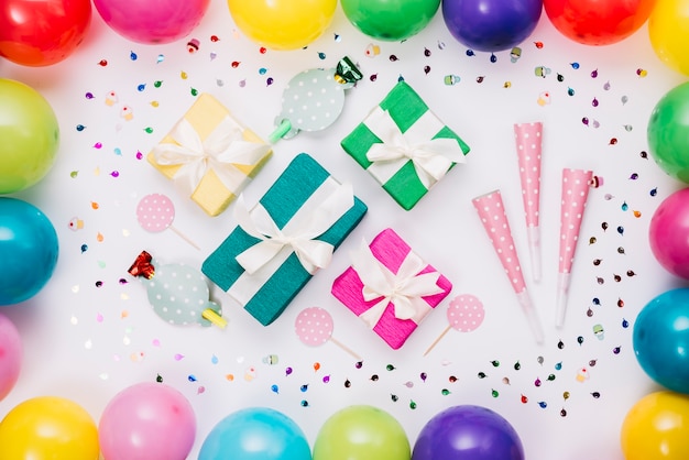 Bunte Geschenkboxen; Partyhorn; Requisite dekoriert mit Konfetti und Luftballons