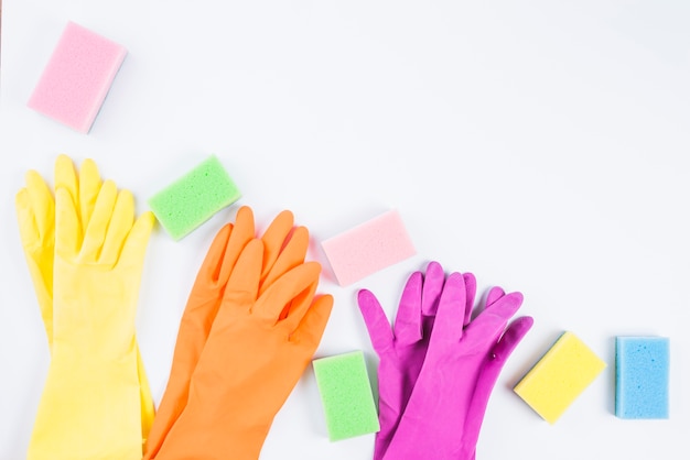 Bunte Handschuhe und Schwamm auf weißem Hintergrund