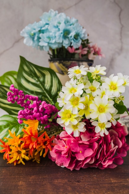 Bunte künstliche Blumen auf hölzernem Schreibtisch