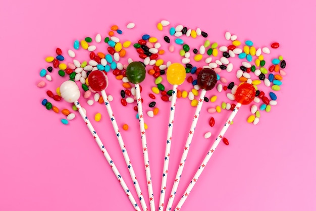 Kostenloses Foto bunte lutscher der draufsicht zusammen mit farbigen bonbons auf rosa, süßem zucker