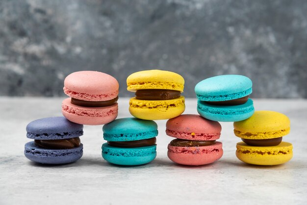 Bunte Mandelmacarons mit Sahne auf weißem Tisch.