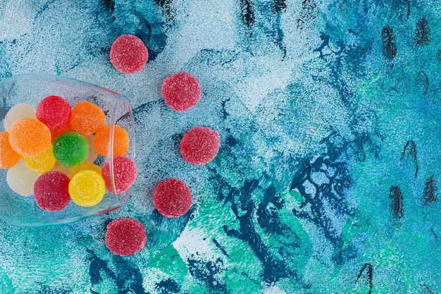 Bunte Marmeladenbonbons in einem Glas, auf dem blauen Hintergrund.