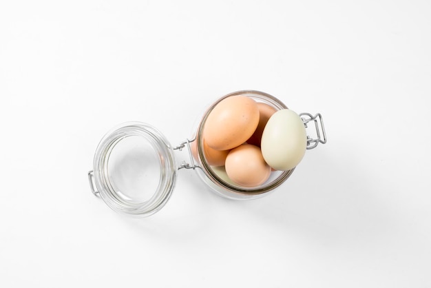 Bunte natürliche eier im glasgefäß lokalisiert auf draufsicht des weißen hintergrundes