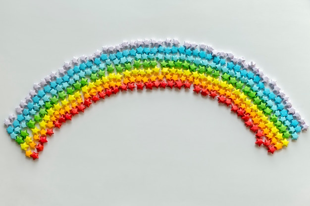 Kostenloses Foto bunte origami-sterne, die einen regenbogenhintergrund bilden