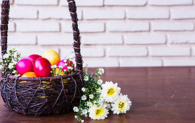 Bunte Ostereier im braunen Korb mit Blumen