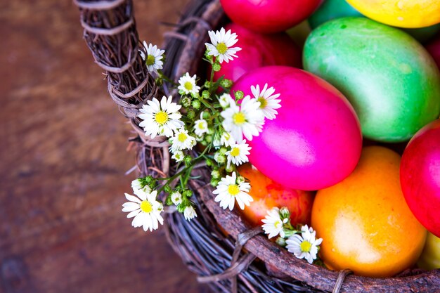 Bunte Ostereier im braunen Korb mit Blumen