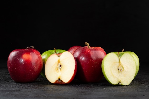 Bunte Äpfel frisch reifen milden saftigen halben Schnitt isoliert auf dunklem Schreibtisch