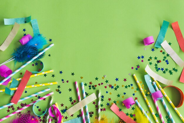 Bunte Sticks mit Konfetti darunter auf einem grünen Tisch