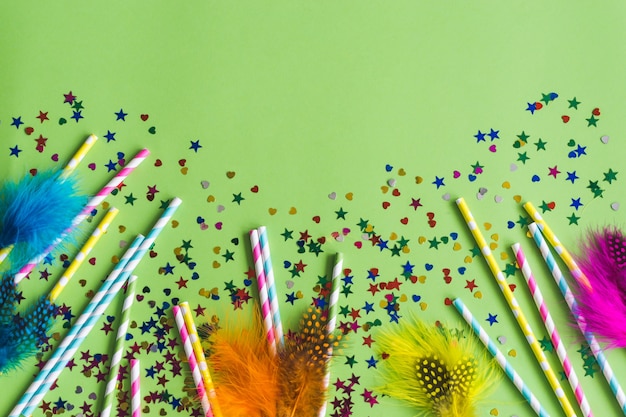 Bunte Sticks mit Konfetti darunter auf einem grünen Tisch