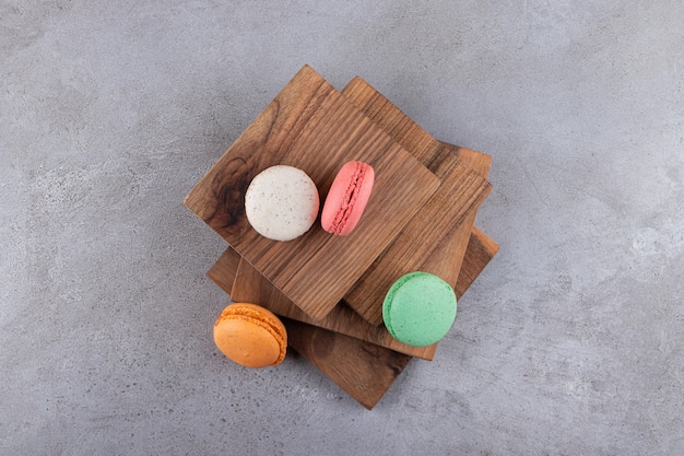 Bunte süße Macaron-Desserts auf Holzbrett gelegt.