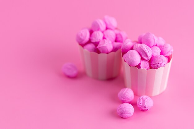 Bunte Süßigkeiten der Vorderansicht auf rosa, süßer Zuckerfarbe der Süßigkeit