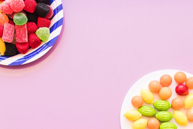 Bunte Süßigkeitsplatte auf der rosa Hintergrundecke