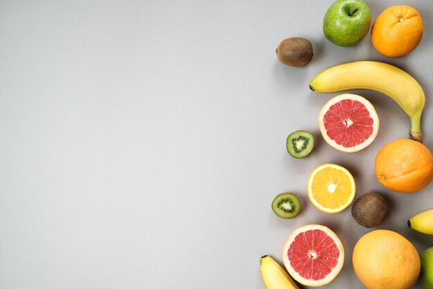 Buntes frisches Obst auf grauem Tisch Orange Bananenäpfel Kiwi Grapefruit Flach lag Draufsicht Kopierbereich Fruchthintergrund