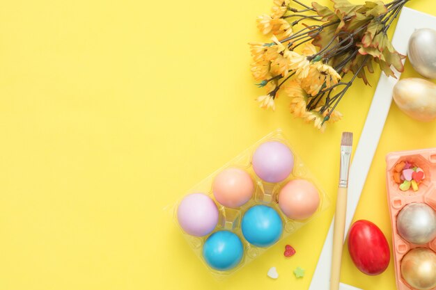 Buntes Osterei der Draufsicht der Draufsicht legen gemalt in der Pastellfarbzusammensetzung und in den Frühlingsblumen