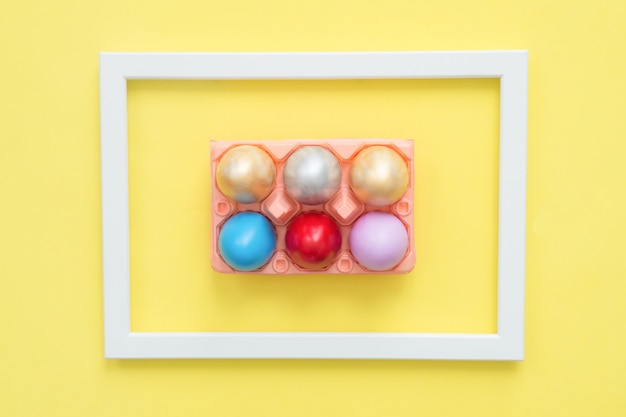 Buntes Osterei der Draufsicht der Ebene legen gemalt in der Pastellfarbzusammensetzung auf gelber Pastellfarbe