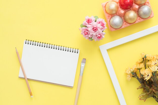 Buntes Osterei der Draufsicht der Ebene legen gemalt in der Pastellfarbzusammensetzung und verspotten herauf leeres Notizbuch