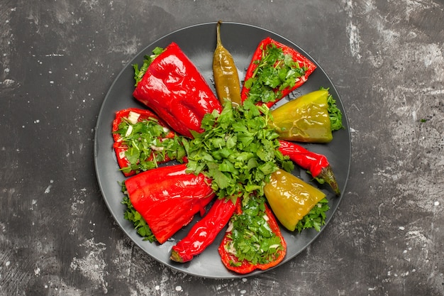 Buntes Pfeffer der oberen Nahansicht verschiedene Arten von Paprika mit Kräutern auf dem schwarzen Teller