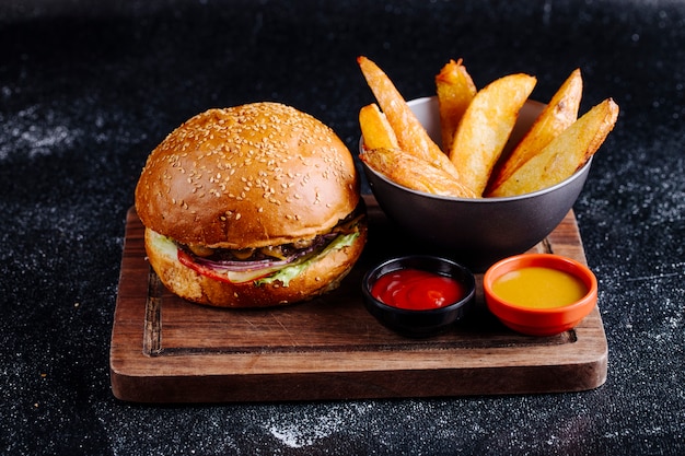 Kostenloses Foto burgerbrötchen, bratkartoffeln in einer schwarzen schüssel mit ketschup und senf.