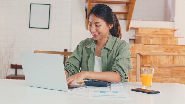 Business Asian Women Aufzeichnungen von Einnahmen und Ausgaben zu Hause