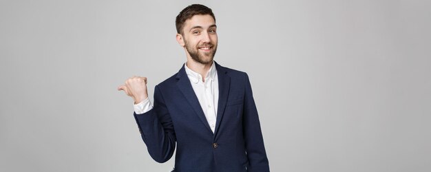Business Concept Portrait junger erfolgreicher Geschäftsmann zeigt mit dem Finger auf dunklem Hintergrund Kopierbereich