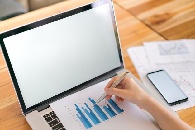 Business-Frau Hand mit finanziellen Charts und Laptop auf dem Tisch.