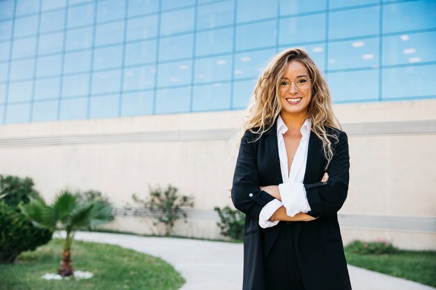 Business-Frau mit Brille vor Glasgebäude