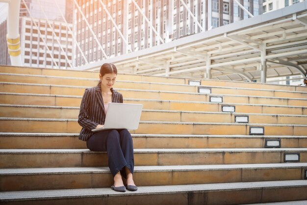 Business-Frau mit Laptop sitzt auf den Stufen. Geschäftsleute Konzept.