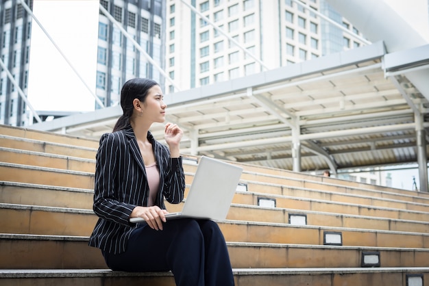 Business-Frau mit Laptop sitzt auf den Stufen. Geschäftsleute Konzept.
