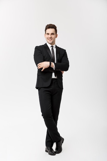 Business-Konzept: Gut aussehender Mann glückliches Lächeln Junger gutaussehender Kerl im eleganten Anzug posiert über isolierten grauen Hintergrund.