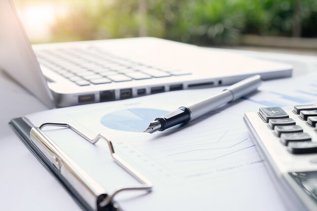 Business-Konzept mit Kopie Raum. Büro Schreibtisch Tisch mit Stift Fokus und Analyse-Diagramm, Computer, Notebook, Tasse Kaffee auf Schreibtisch.Vintage Ton Retro-Filter, selektiven Fokus.