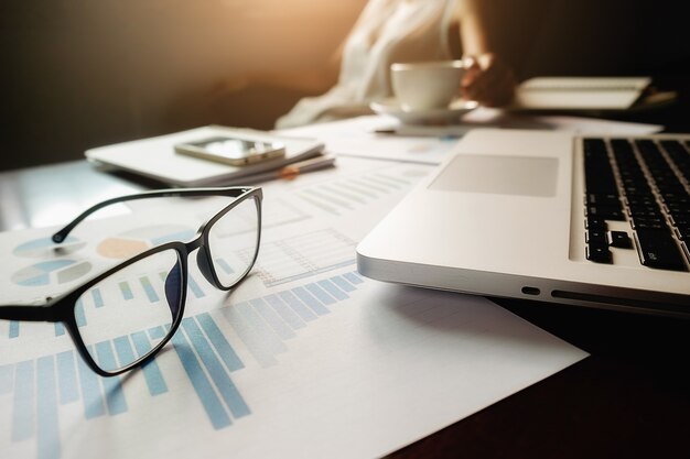 Business-Konzept mit Kopie Raum. Büro Schreibtisch Tisch mit Stift Fokus und Analyse-Diagramm, Computer, Notebook, Tasse Kaffee auf Schreibtisch.Vintage Ton Retro-Filter, selektiven Fokus.