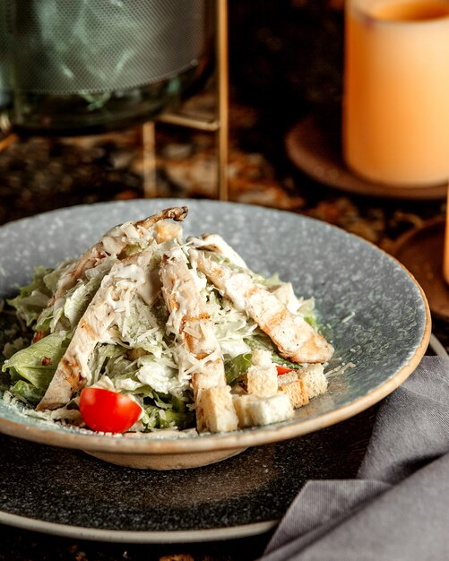 Caesar Salat mit Huhn, Salat, Tomaten, Crackern und geriebenem Käse